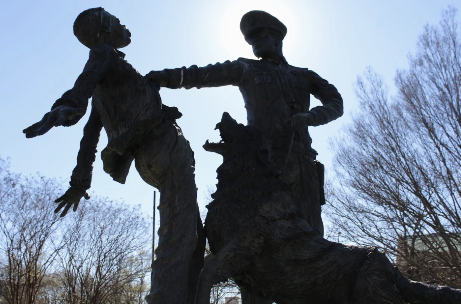 A statue depicts a law enforcement officer and a dog attacking a young person.