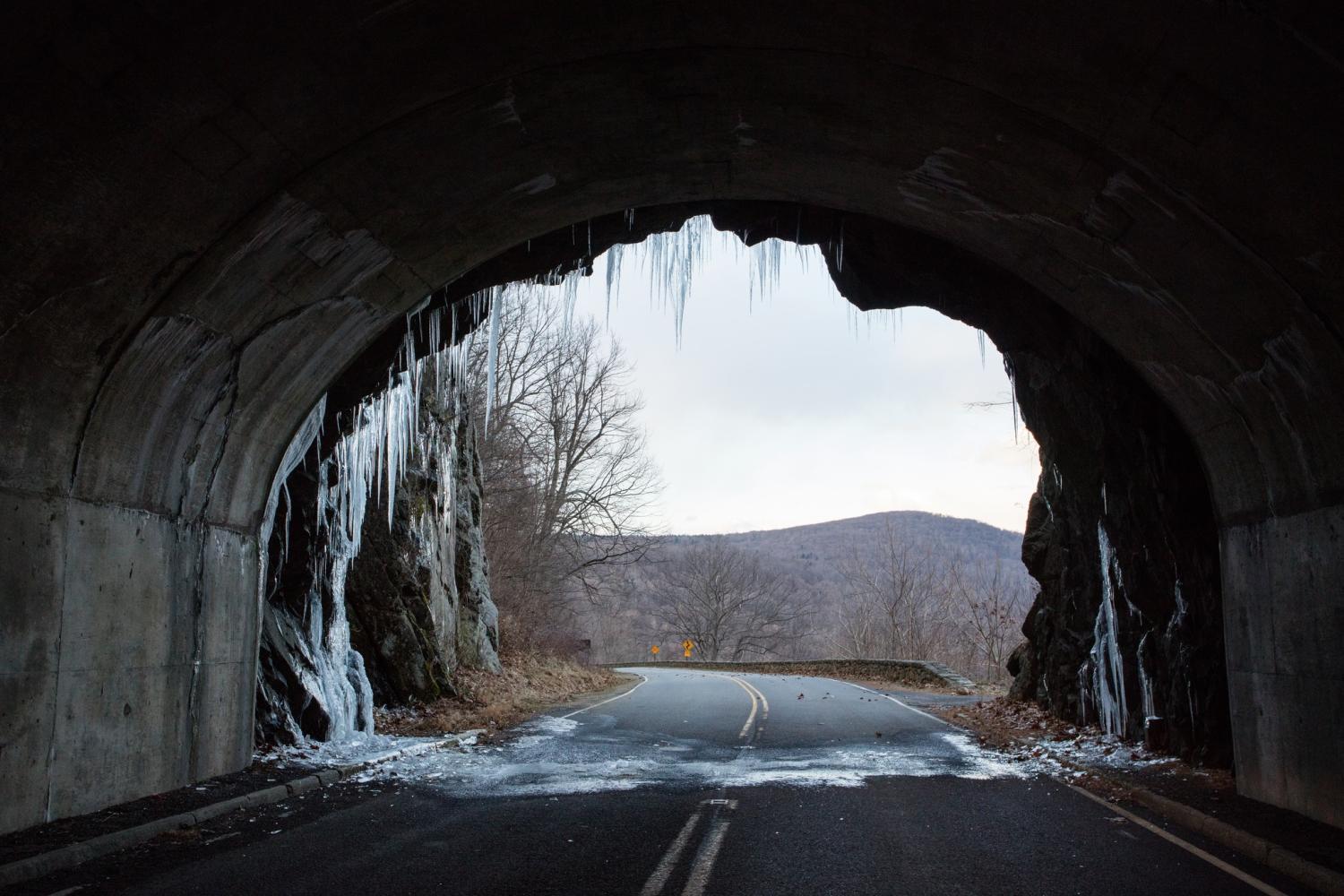 Icicles line a tunnel exit and fallen ice sits on the road below.