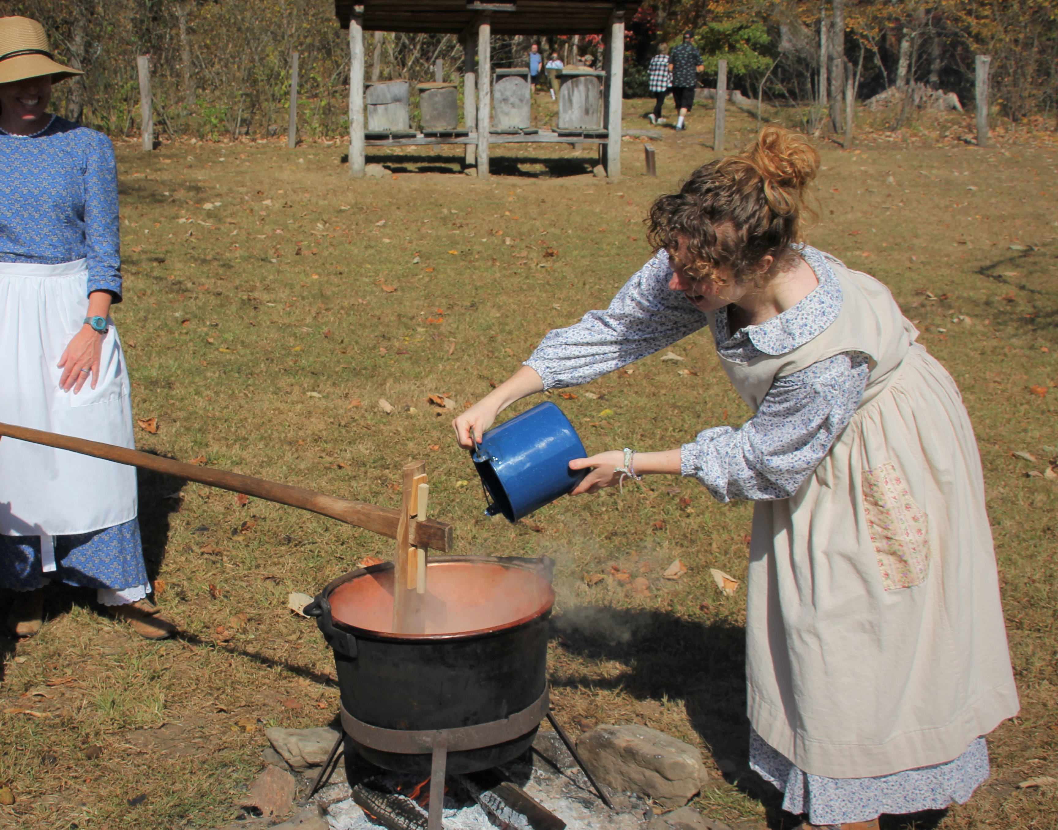 A woman in a pioneer dress churns butter.