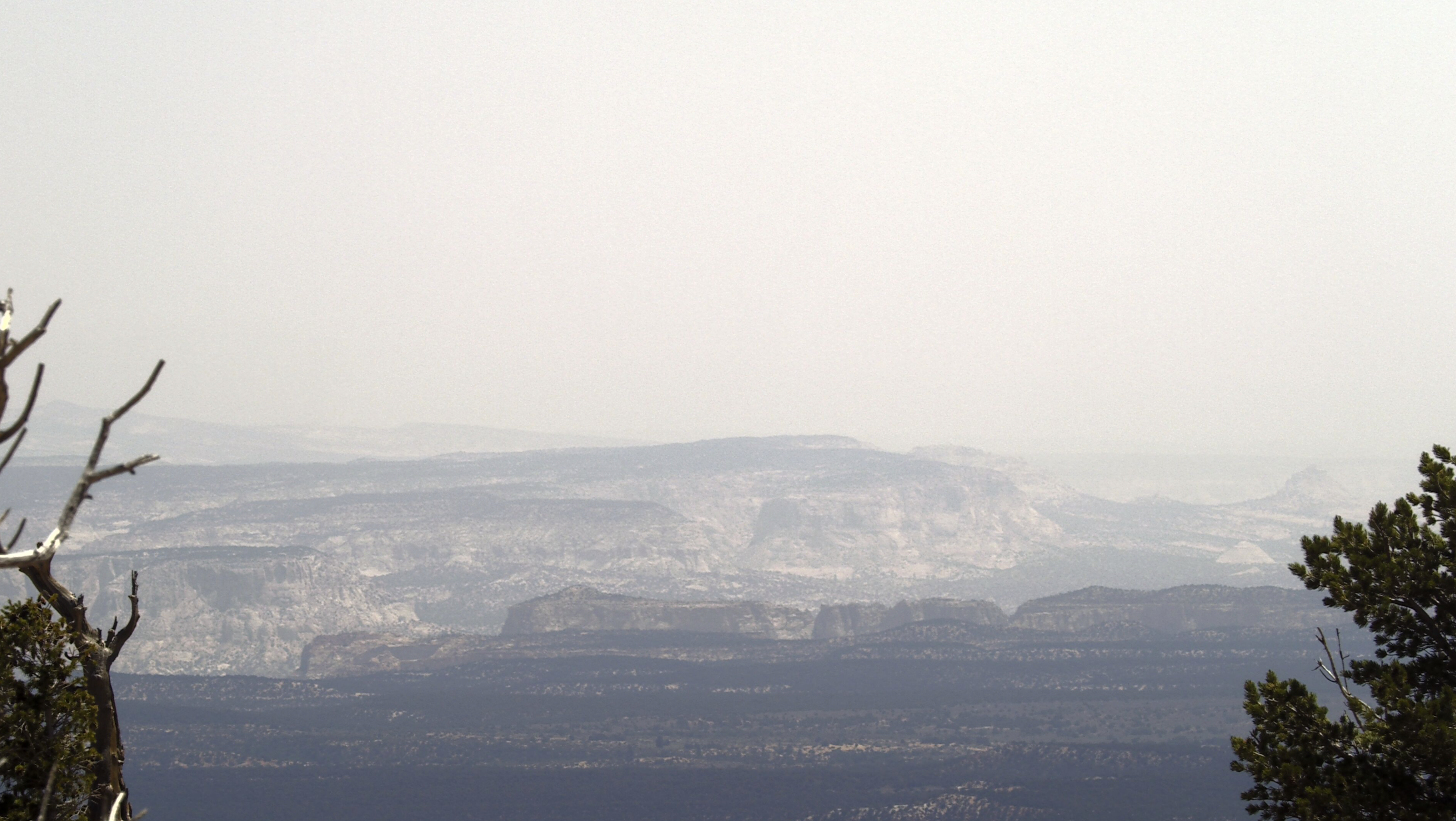 Mountains with bands of colors are surrounded by a hazy skie.