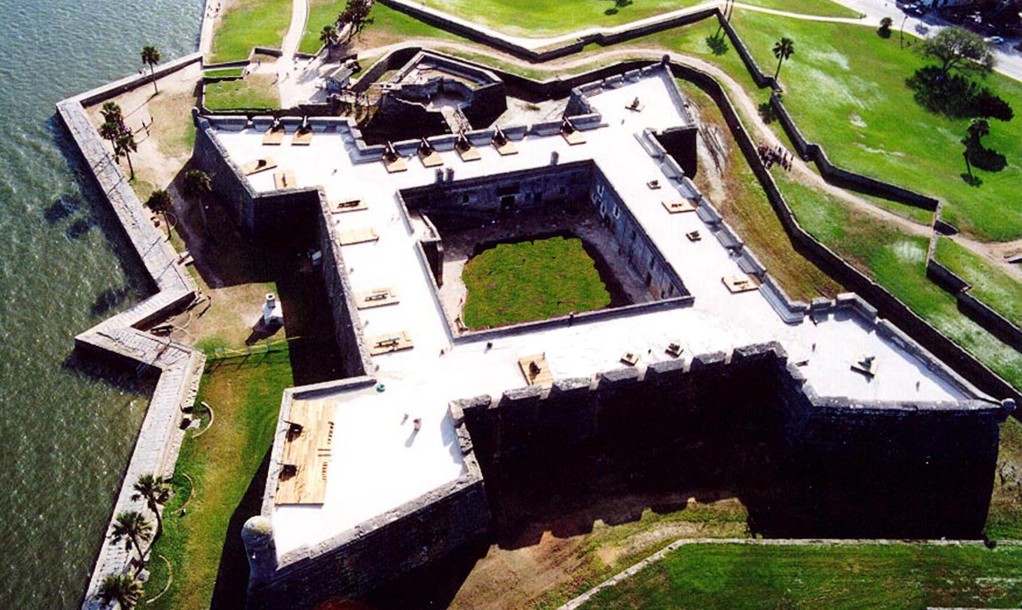 An aerial view of a fortress next to water.