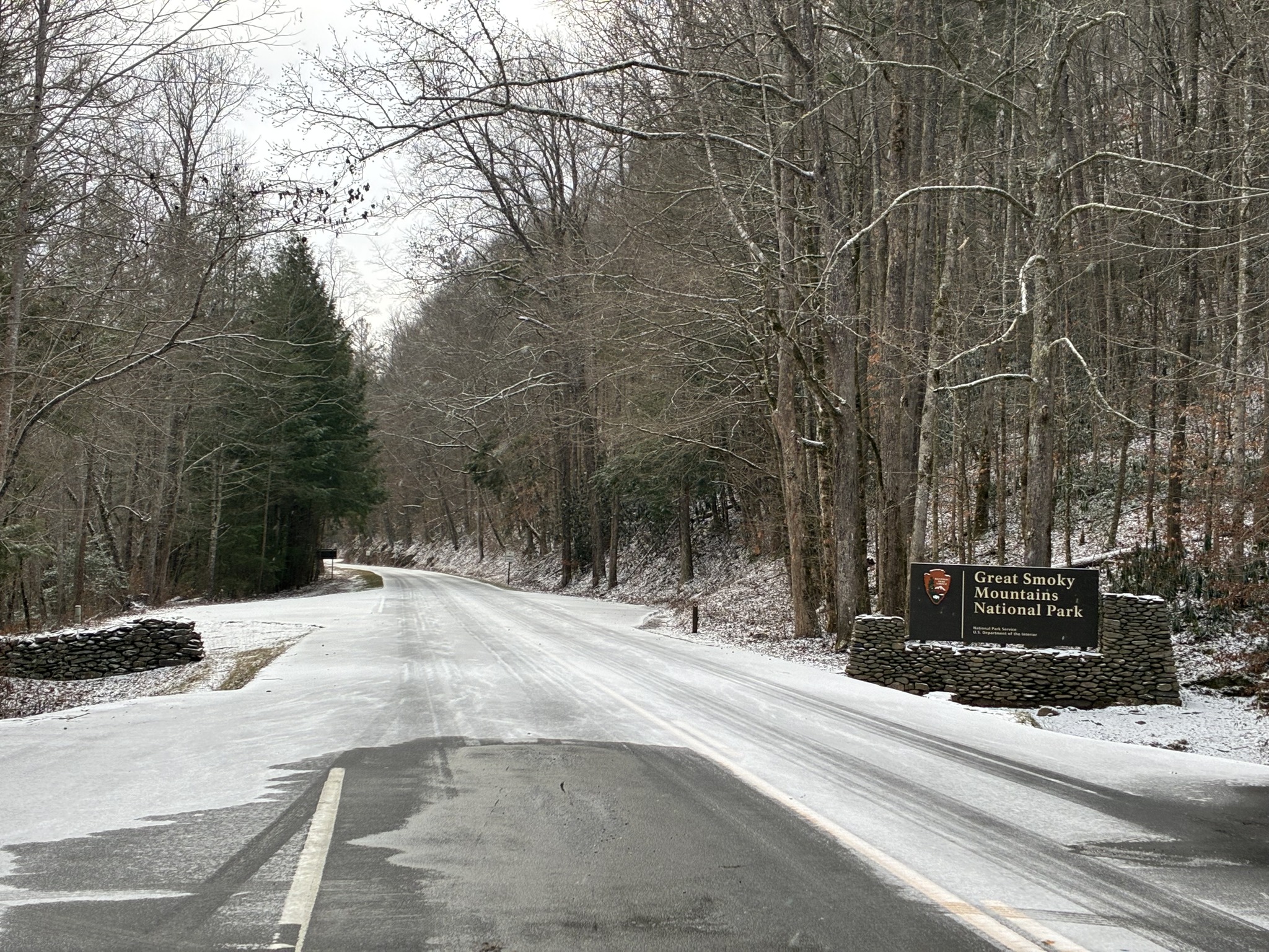 A sign for Great Smoky Mountains National Park sits alongside an icy road.