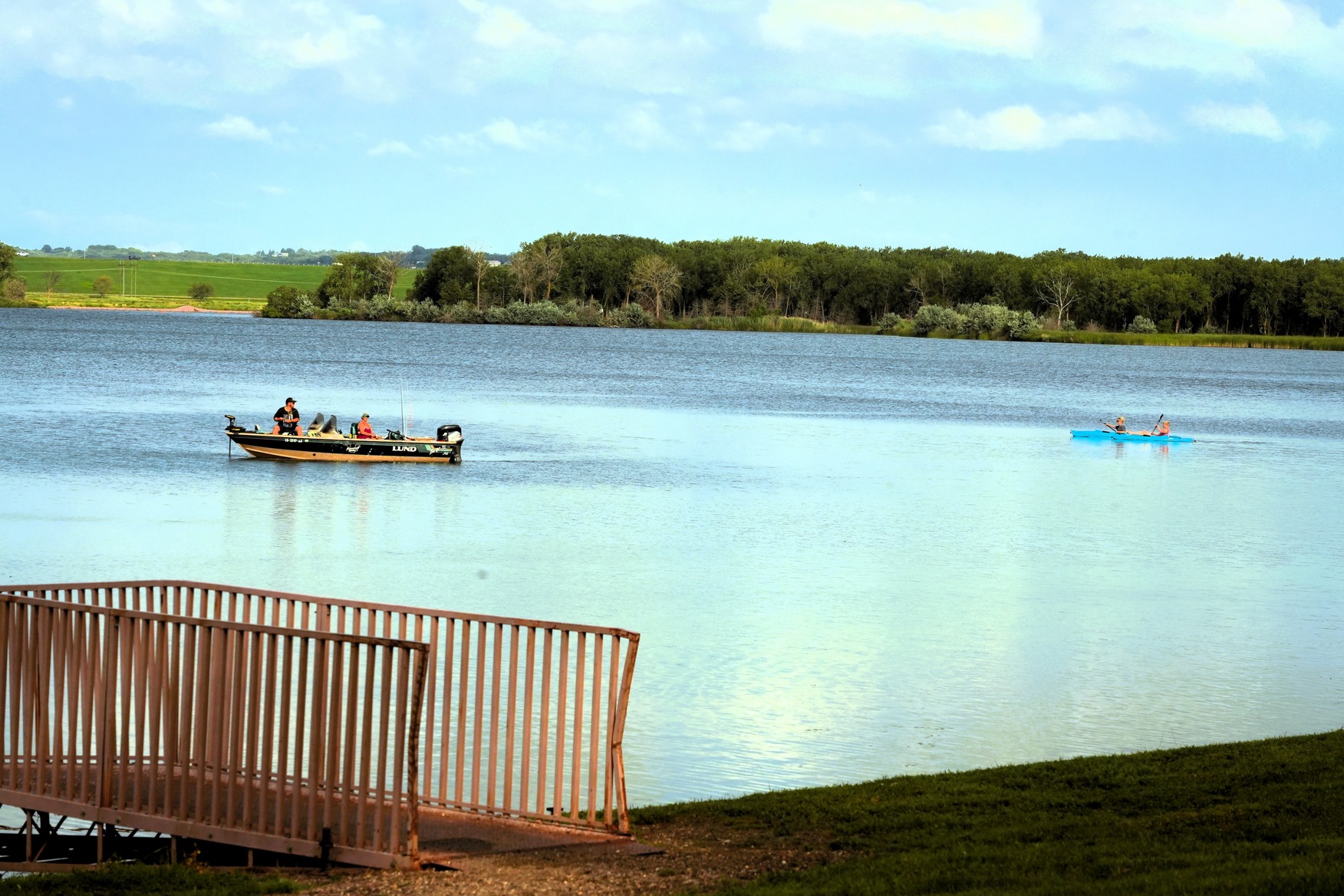 Two people in a fishing boat followed by two people in a tandem kayak on Lake Yankton.