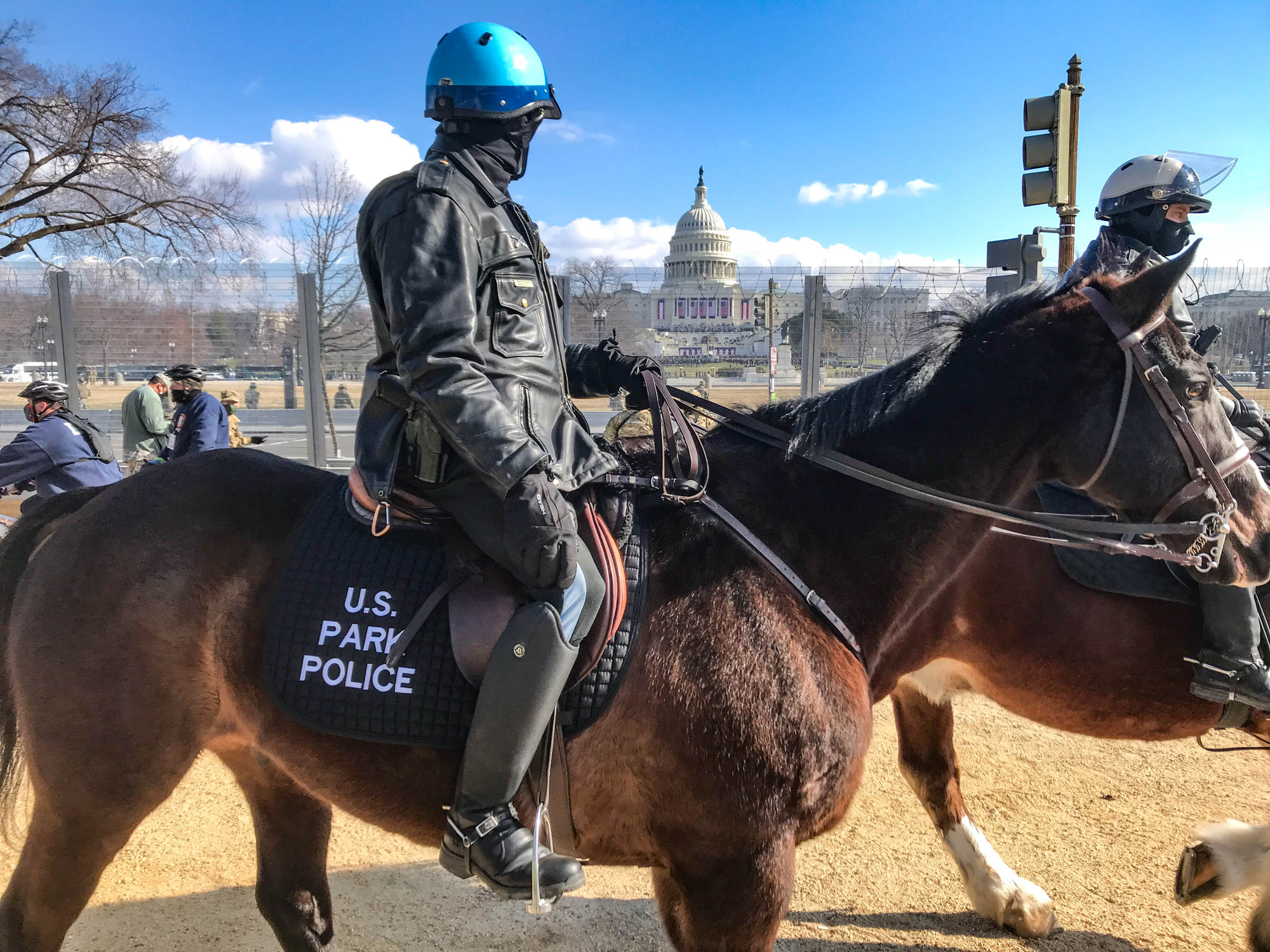 A horse-mounted U.S. Park Police officer riding along a fence near the U.S. Capitol building