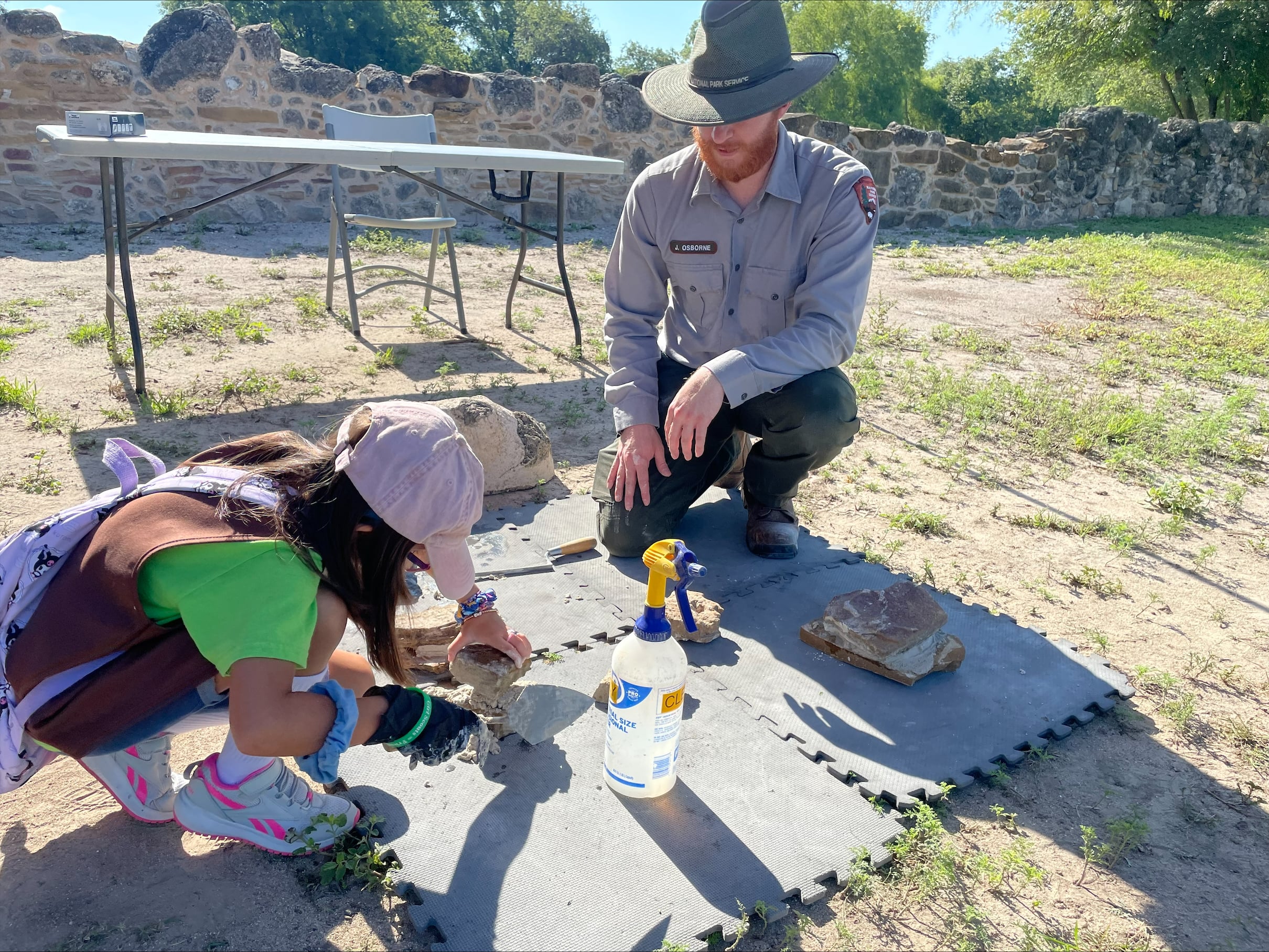 A park ranger shows a young girl how to do simple masonry work at Junior Ranger Day