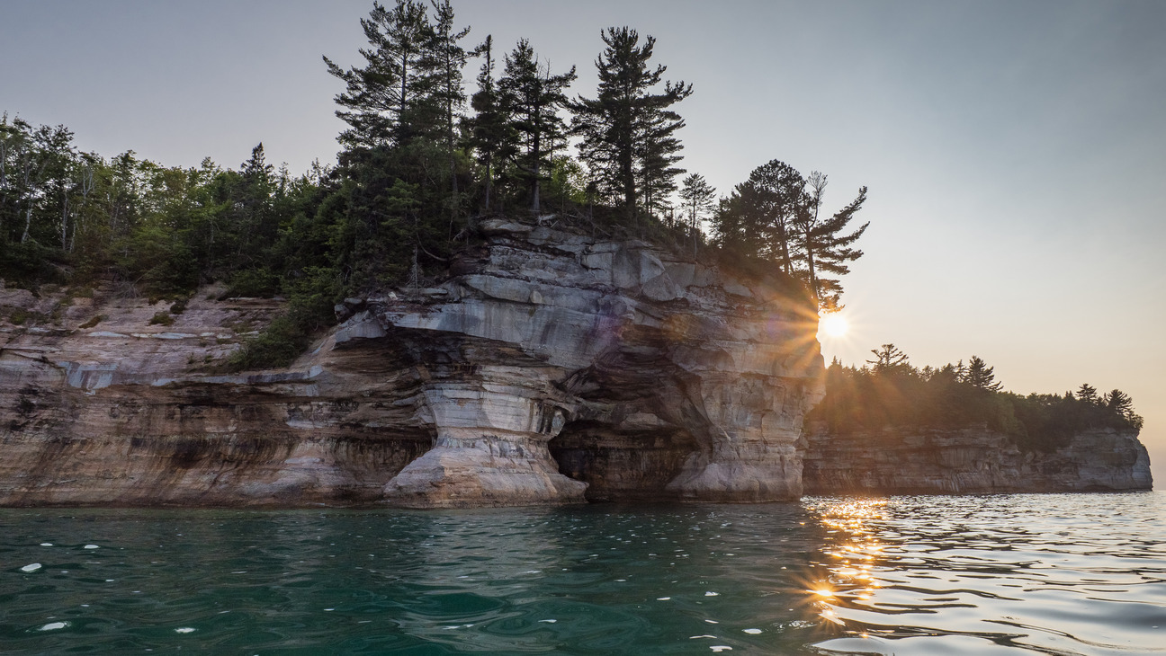 Sandstone cliffs rise out of Lake Superior on a sunny day.