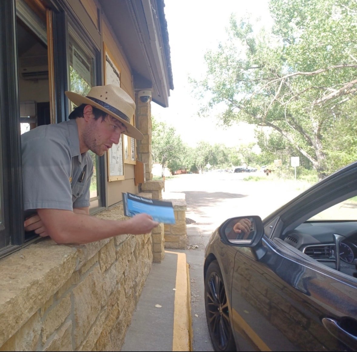 A park ranger hands a brochure to a visitor