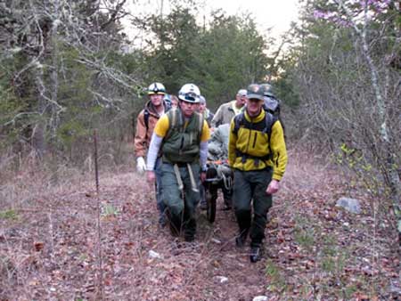 Rescuers carry victim toward waiting helicopter.