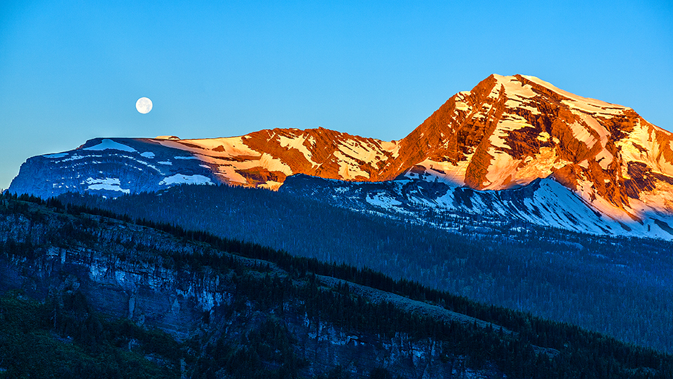 Moonset and sunrise over Heavens Peak, Glacier National Park / Rebecca Latson Moonset and sunrise over Heavens Peak, Glacier National Park / Rebecca Latson