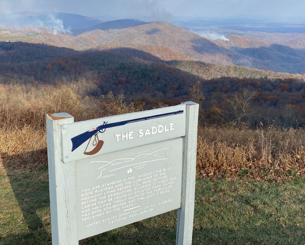 Looking beyond an interpretive sign at milepost 168 on the Blue Ridge Parkway, smoke from the Tuggle’s Gap fire is seen in the distance/NPS Looking beyond an interpretive sign at milepost 168 on the Blue Ridge Parkway, smoke from the Tuggle’s Gap fire is seen in the distance/NPS