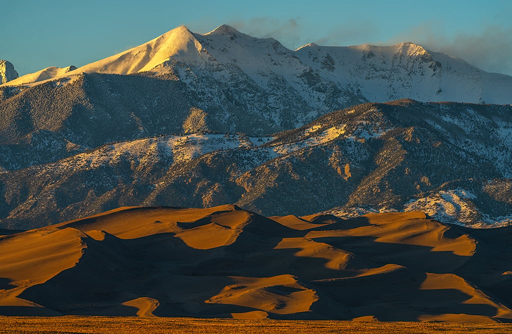 A telephoto sunset over mountains and dunes, Great Sand Dunes National Park and Preserve / Rebecca Latson A telephoto sunset over mountains and dunes, Great Sand Dunes National Park and Preserve / Rebecca Latson