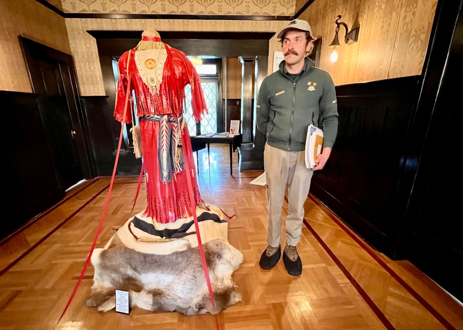 Parks Canada heritage interpreter Bennie Allain on the "Red Serge, Red Tape" tour of the Commissioner's Residence stands by artist Faye Chamberlain's thought-provoking dress. Parks Canada heritage interpreter Bennie Allain on the "Red Serge, Red Tape" tour of the Commissioner's Residence stands by artist Faye Chamberlain's thought-provoking dress.