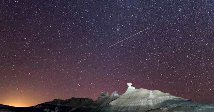 Stars shine over rock formations in Petrified Forest National Park, with the dim glow of Holbrook, Arizona, on the horizon to the west. Photo by Jake Holgerson/NPS. Stars shine over rock formations in Petrified Forest National Park, with the dim glow of Holbrook, Arizona, on the horizon to the west. Photo by Jake Holgerson/NPS.