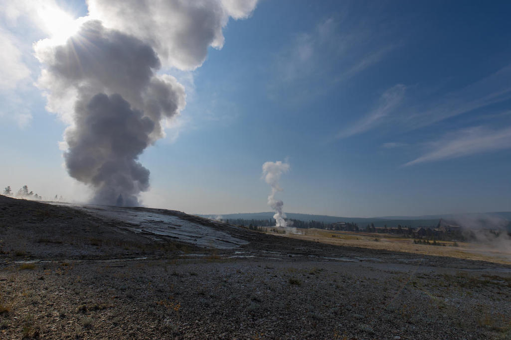 Giantess Geyser in eruption at approximately 10:00 AM MDT on August 26, 2020.  Old Faithful is erupting in the center background/NPS, Stan Mordensky