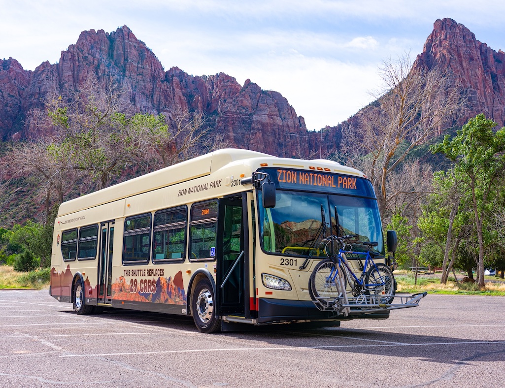 One of the new electric shuttle bus in front of The Watchman in Zion National Park/NPS, Colton Johnston