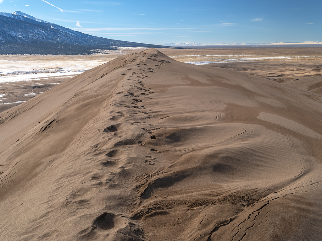 A footprint-covered dune ridge looking south toward the Sangre de Cristo Mountains and San Luis Valley at Great Sand Dunes National Park and Preserve