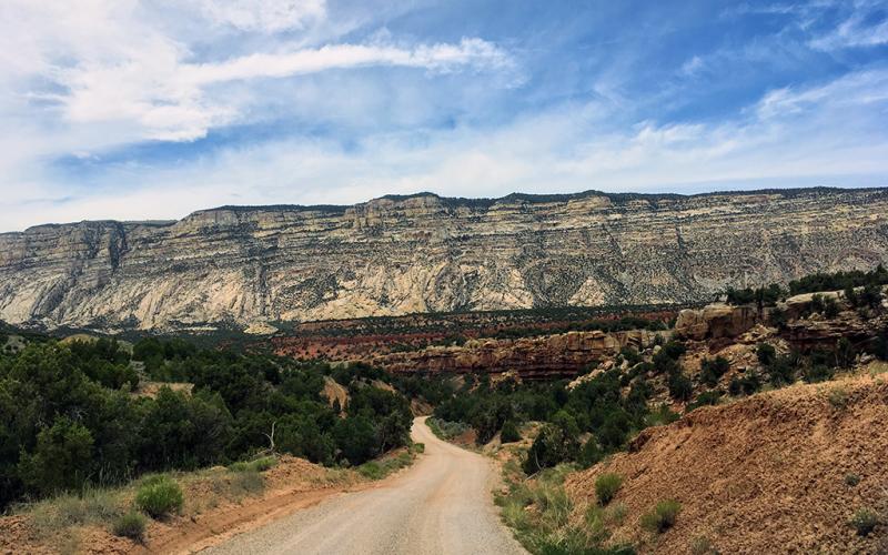 Echo Park Road winds away towards geologic features of many colors towering in the distance in Dinosaur National Monument