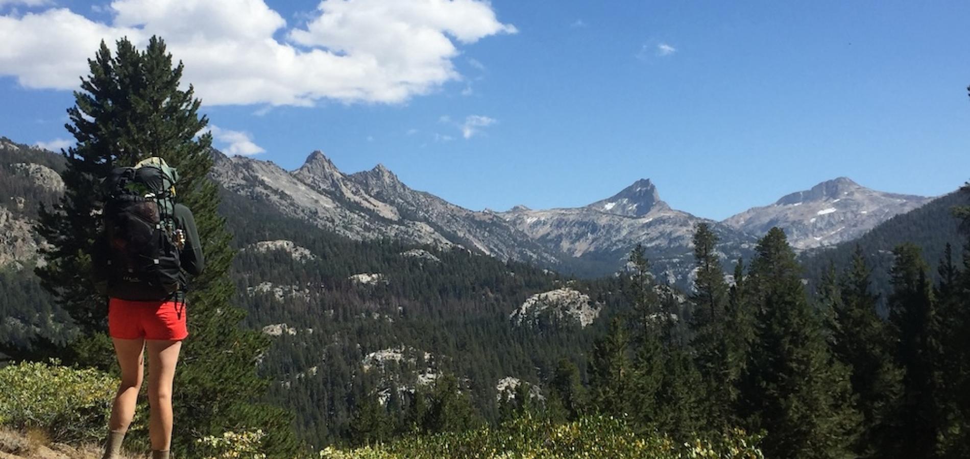 Woman looks at distant mountain peaks
