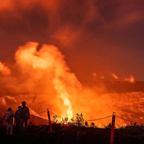 A crowd watching a night time volcano eruption at Hawaii Volcanoes National Park