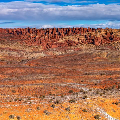 A sunny view of Salt Valley with the formations of Fiery Furnace in the distance at Arches National Park in Utah