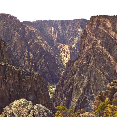 A chasm view of the pink-veined cliffs and the Gunnison River below at Black Canyon of the Gunnison National Park