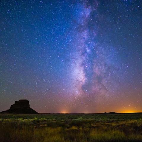 Fajada Butte stands in silhouette against the night sky and Milky Way at Chaco Culture National Historical Park, NM.