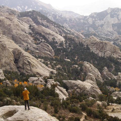 A lone hiker acts as scale and reference among the vast, rocky mountains of City of Rocks National Reserve