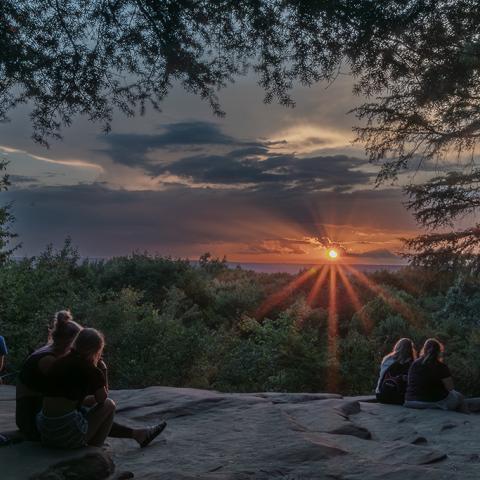 People sitting on a rock ledge watching a sunset at Cuyahoga Valley National Park