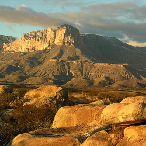Rocks and the awe-inspiring ancient uplifted El Capitan reef glowing with light from a setting sun at Guadalupe Mountains National Park