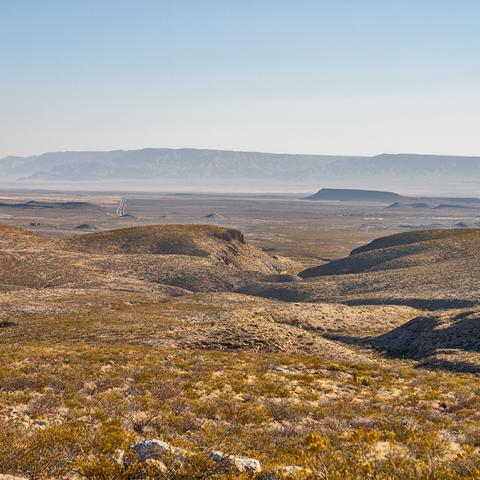 A hazy wide-angle view of arid mountains and valleys within far West Texas, just beyond the boundary of Guadalupe Mountains National Park