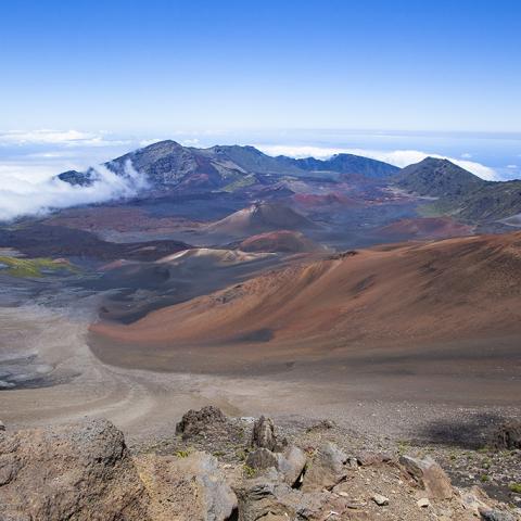 A wide-angle vista of clouds, cinder cones and other volcanic scenery in Haleakala National Park in Hawaii