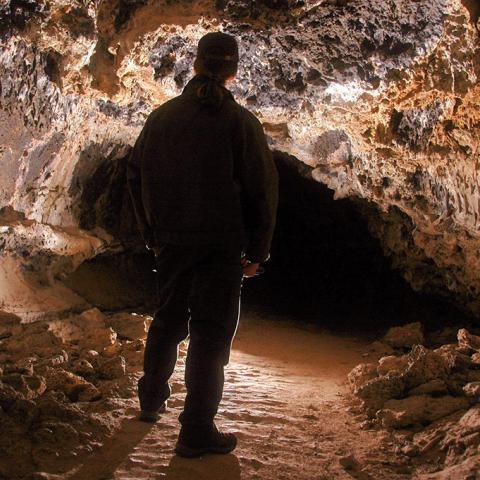 Cave Specialist Shane Fryer looking through a side tube of Catacombs Cave, Lava Beds National Monument