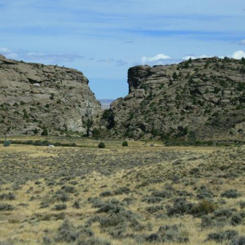 A gap in between two rock buttresses with blue sky and sagebrush in the foreground, Mormon Pioneer National Historic Trail
