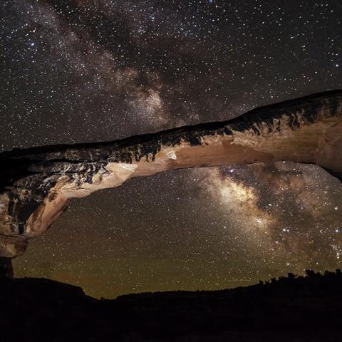 The arching rock formation known as Owachomo Bridge frames this view of the Milky Way overhead at Natural Bridges National Monument, Utah.