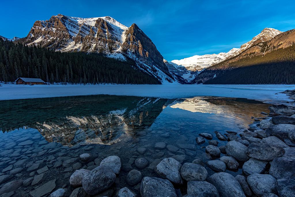 A clear, sunny, spring morning at Lake Louise, with snow-capped mountains reflecting in the lake at Banff National Park in Canada