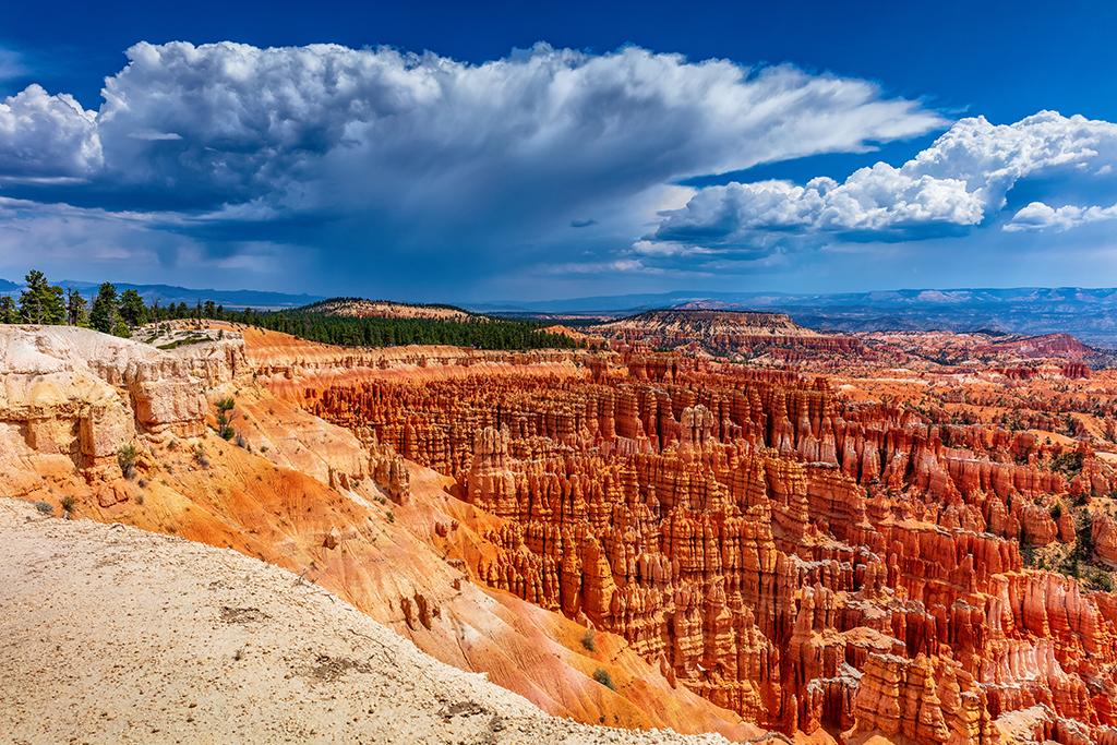 A large, ominous storm cloud bringing monsoon rains hovering over the red-rock hoodoos of Bryce Amphitheater in Bryce Canyon National Park
