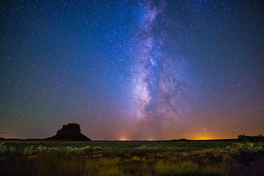 Fajada Butte stands in silhouette against the night sky and Milky Way at Chaco Culture National Historical Park, NM.
