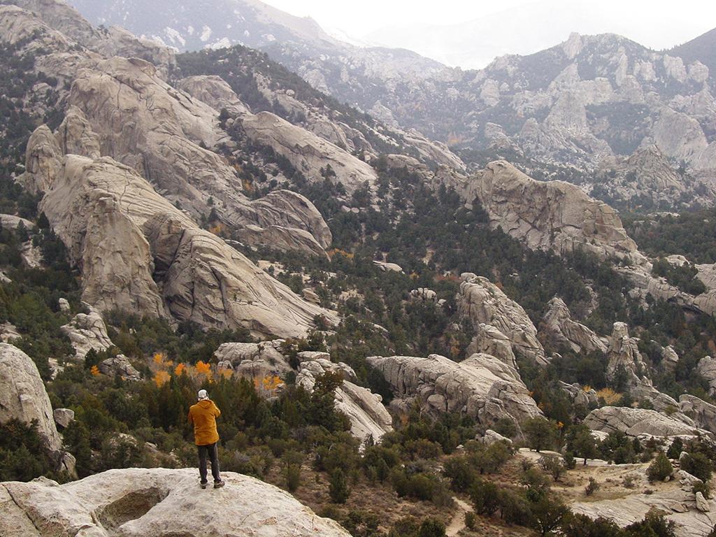 A lone hiker acts as scale and reference among the vast, rocky mountains of City of Rocks National Reserve