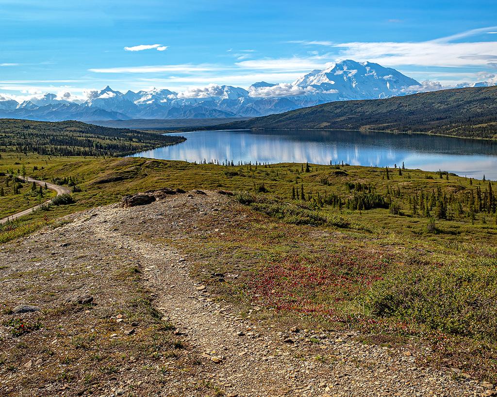 A dirt and gravel trail that parallels Wonder Lake on a sunny day in Denali National Park and Preserve