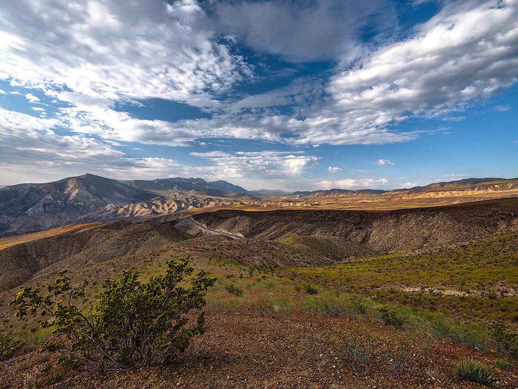 A view of the dry, mountainous landscape seen from Father Crowley Vista Point beneath a blue sky with puffy clouds, Death Valley National Park