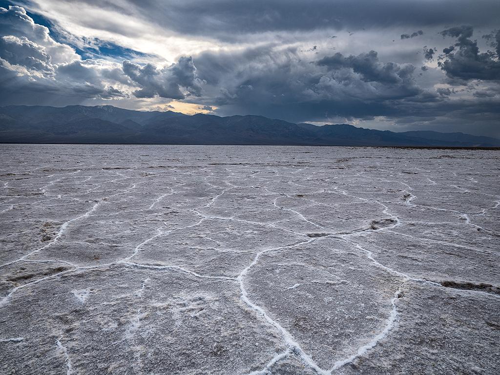 A spooky, overcast afternoon with large rainclouds over the salt flats of Badwater Basin at Death Valley National Park in California