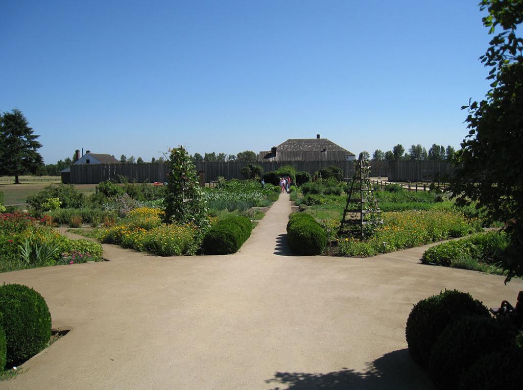 Pathways radiate from a central clearing in the formal, symmetrical garden. Bright flowers direct the view to the fort at Fort Vancouver National Historic Site.