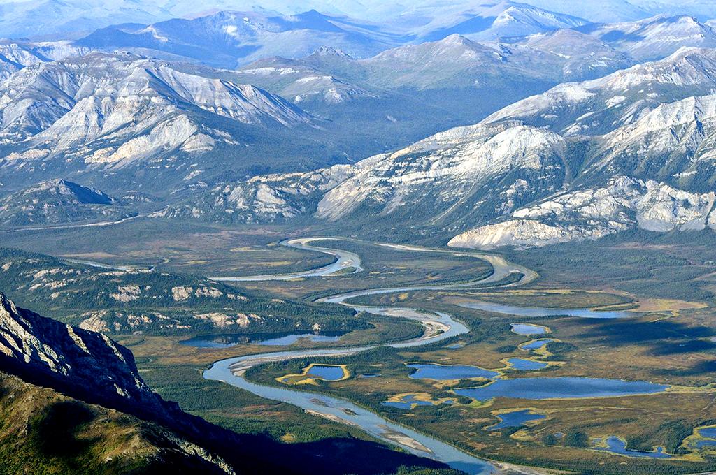 An aerial view of a meandering river flowing through a valley rimmed by snowcapped mountains, Gates of the Arctic National Park and Preserve
