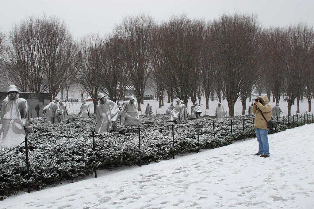 Photographer taking pictures of snow-covered statues of American servicemen