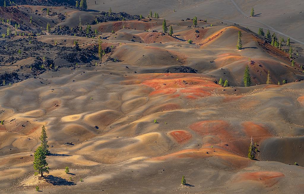 A telephoto view of colorful beige, orange, and yellow pumice dunes seen from the top of Cinder Cone in Lassen Volcanic National Park