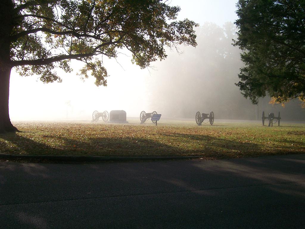 An ethereal, foggy morning of a field with the silhouettes of trees and canons at Silversparre's Battery, Battery H, 1st Illinois Light Artillery, Shiloh National Military Park