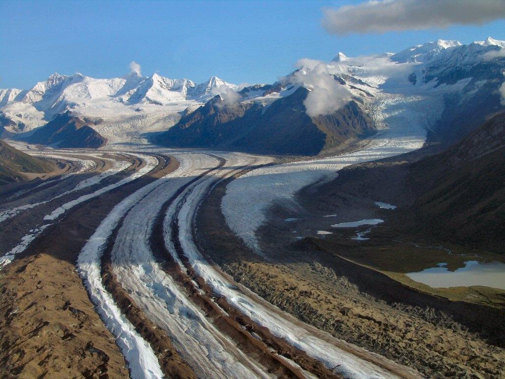 The brown and white stripes of two glaciers merging together at Wrangell-St. Elias National Park and Preserve