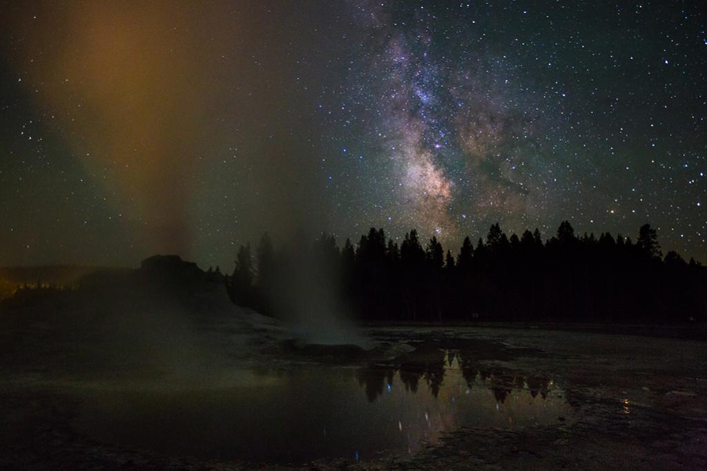 Steaming geysers spray skyward to the starry night at Yellowstone National Park, Wyoming.