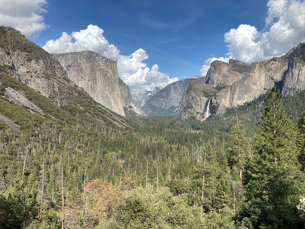 A view of Yosemite Valley from Wawona Tunnel on a blue sky day with white fluffy clouds, Yosemite National Park