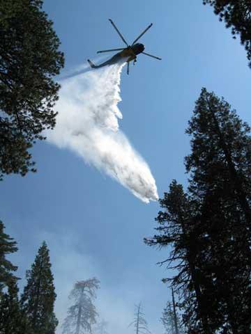 Helicopter dropping water on a fire.